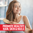Woman smiling while brushing her hair, promoting healthy hair, skin, and nails