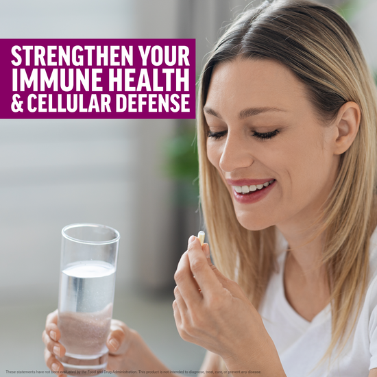 Woman smiling while holding a supplement capsule and glass of water