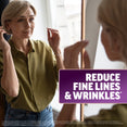 Woman fixing her hair in a mirror, promoting reduced fine lines and wrinkles