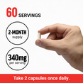 Hand holding a supplement capsule with details about servings and dosage.