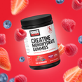 Creatine monohydrate gummies jar surrounded by raspberries and strawberries on a vibrant red background.